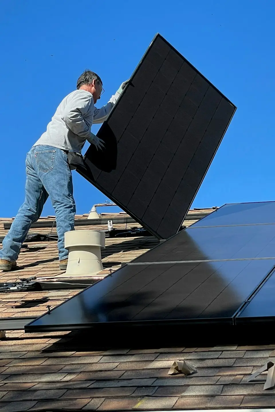 man in white dress shirt and blue denim jeans sitting on white and black solar panel